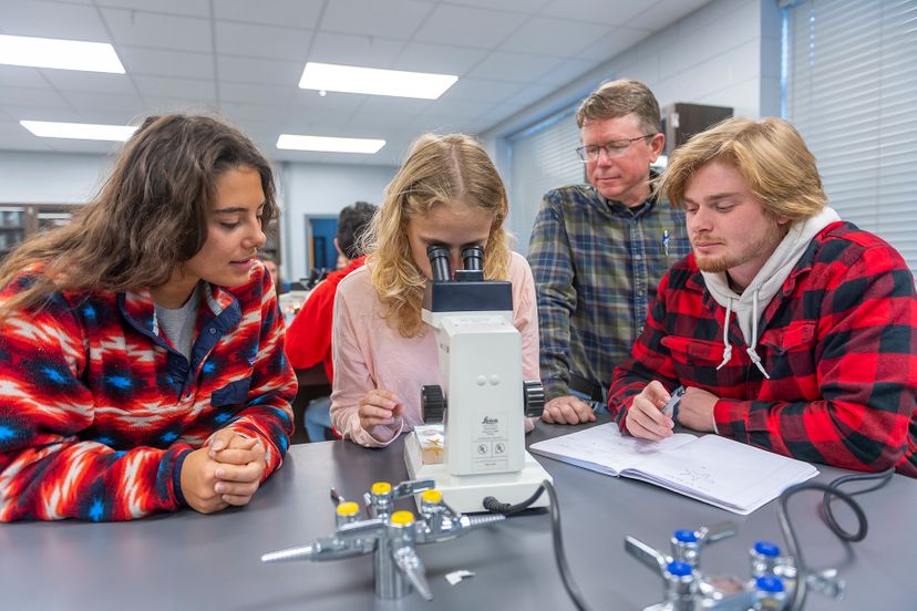 Biology students and faculty with microscope